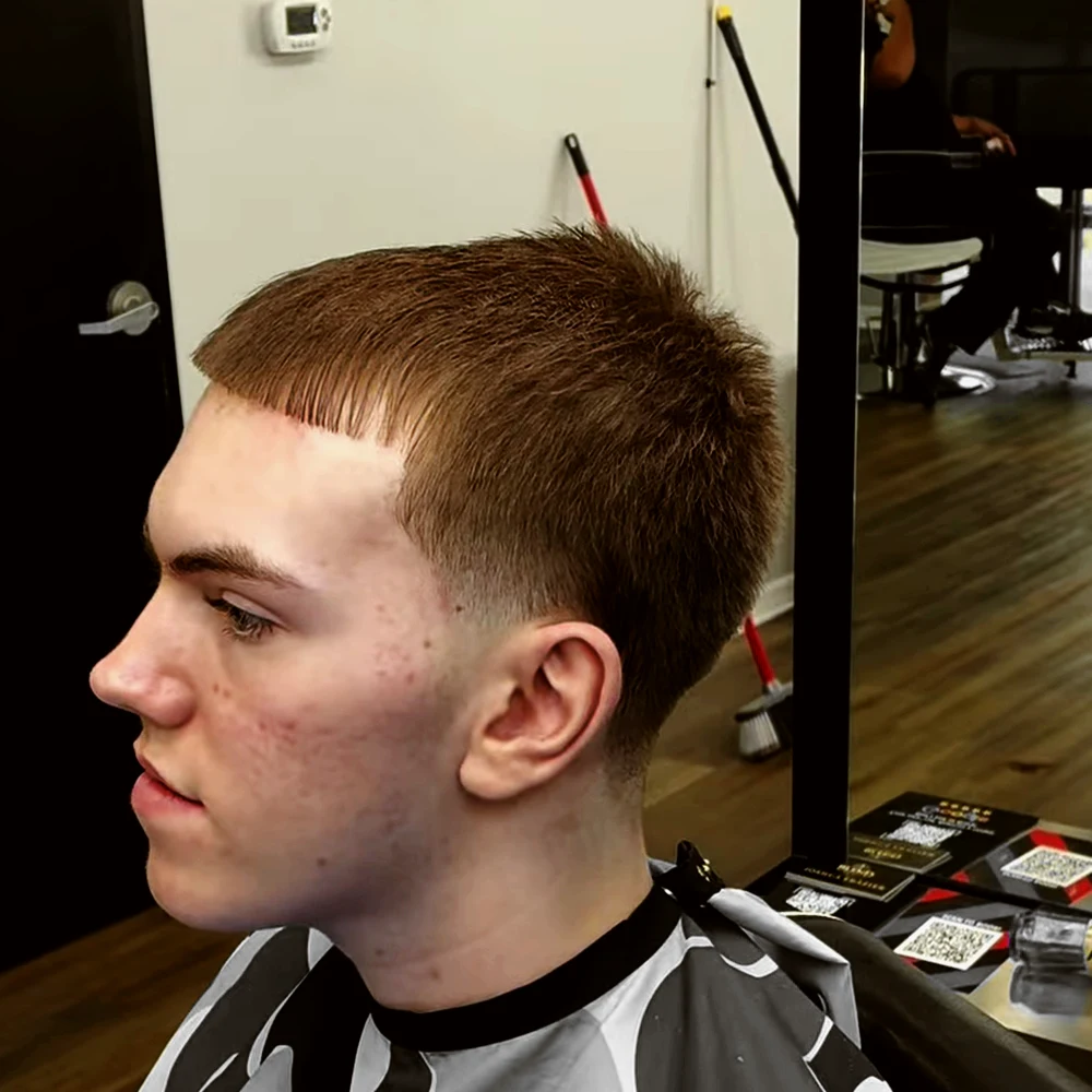 El mismo cliente de perfil, después: corte corto con flequillo y taper